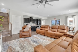 A spacious living room with a large sectional sofa, a recliner, and a patterned rug.