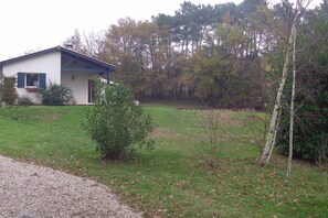 A house with a small front yard, a gravel path, and a dense tree line in the background. - Country house with a pool between Bordeaux and St-Émilion (Croignon)