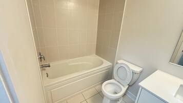 Een badkamer met een bad, toilet en wastafel.