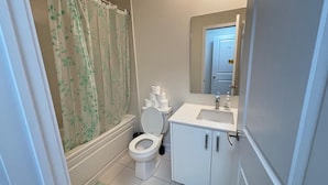 Un baño con inodoro, lavamanos y cortina de ducha.