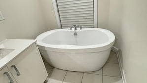 Un baño con bañera independiente, lavamanos e inodoro.