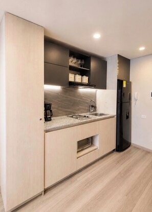 A modern kitchen with a built-in stove, a coffee maker, and a black refrigerator. - Stylish La Cabrera Loft  2 Double Beds near Zona T (Bogotá)