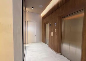 A hallway with a white floor, a wooden wall panel, and a door at the end. - Stylish La Cabrera Loft  2 Double Beds near Zona T (Bogotá)