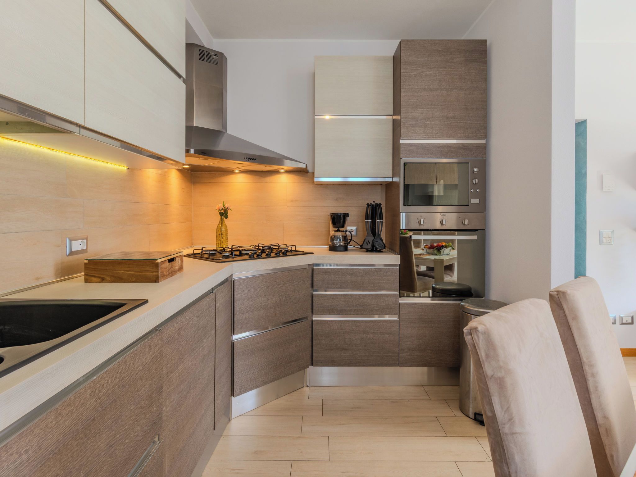 A modern kitchen with built-in appliances, a wooden countertop, and a stainless steel range hood.