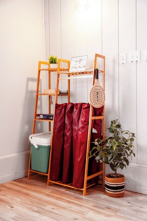 Een stapelbed met een ladder, een rood gordijn, een laptop, een plant en een stopcontact.
