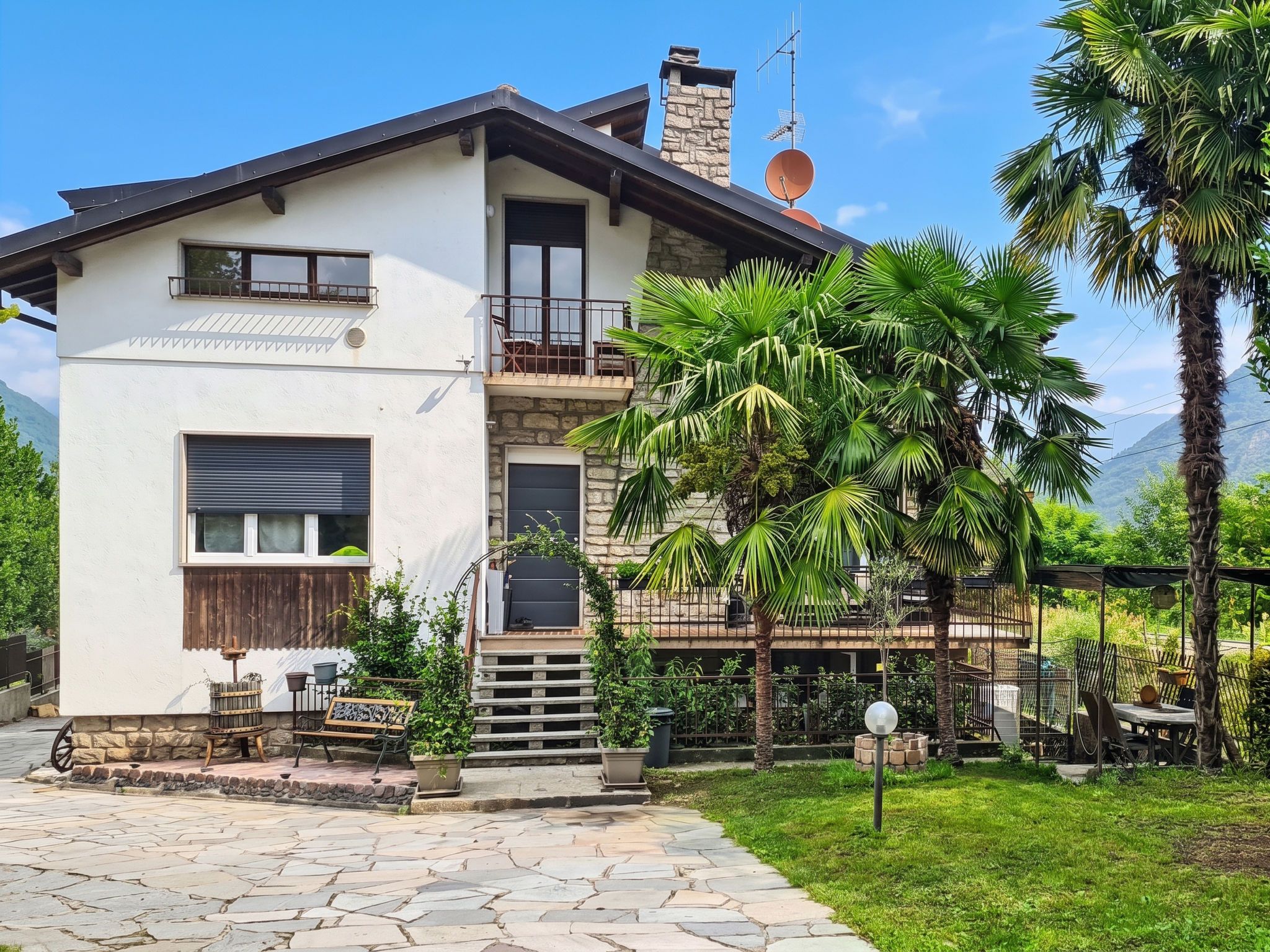 A two-story house with a stone facade, a balcony, and a stone staircase leading to the upper floor.