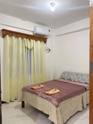 Ein Schlafzimmer mit einem Bett, Vorhängen, einer Klimaanlage und einer Leuchte.