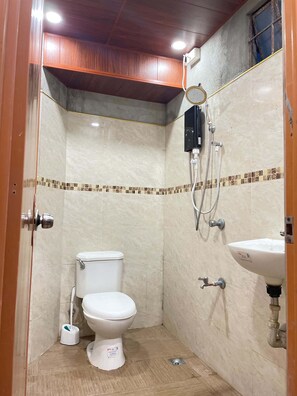 Ein kleines, kompaktes Badezimmer mit Toilette, Waschbecken und Duschkabine.