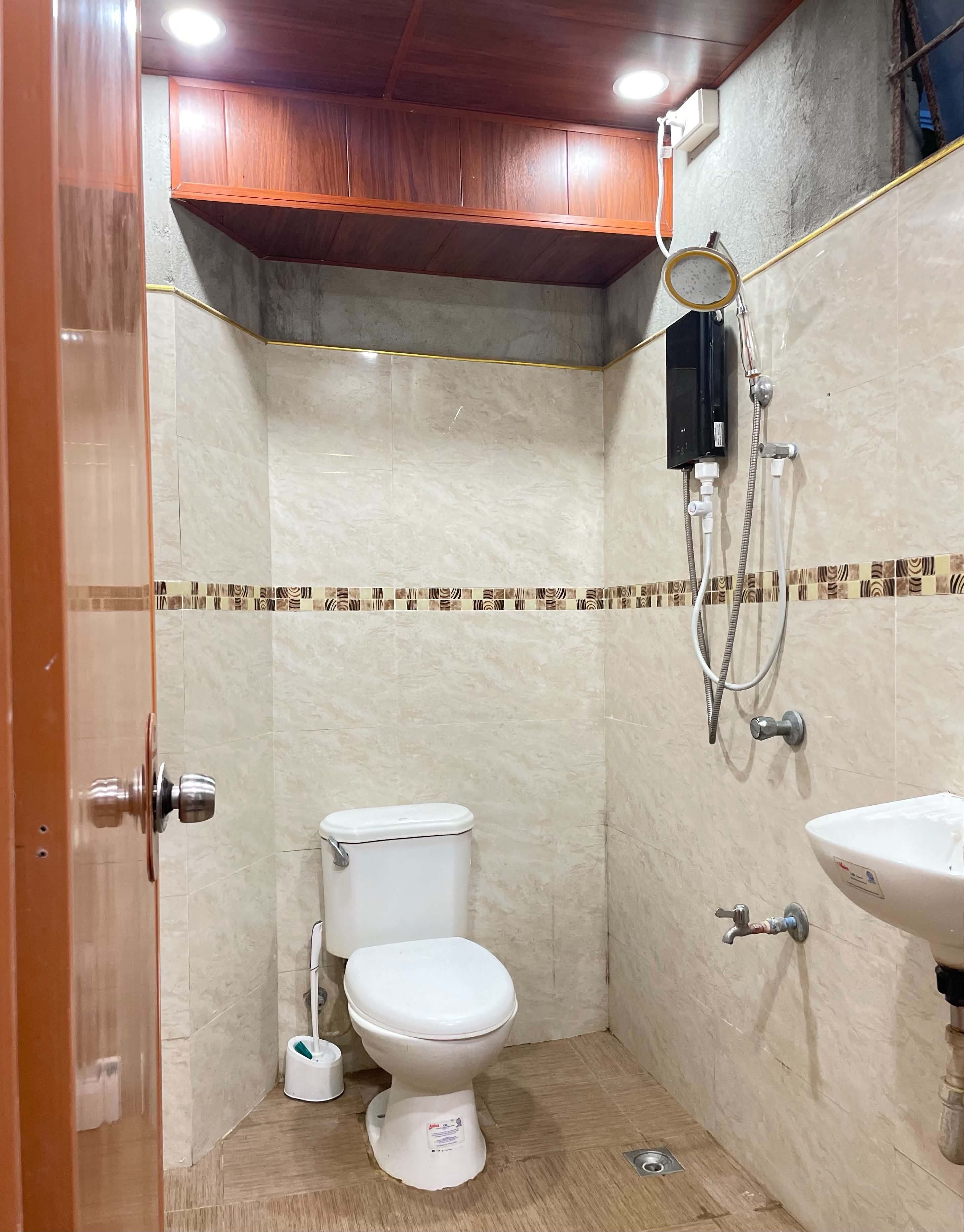 A small, compact bathroom with a toilet, a shower, and a sink.