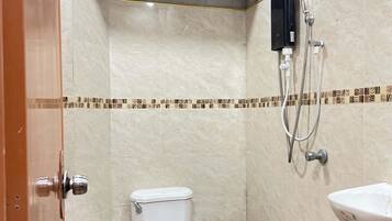 A small, compact bathroom with a toilet, a shower, and a sink.