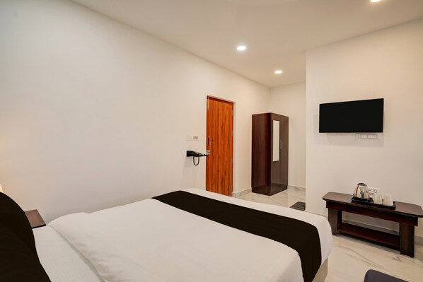 Una habitación de hotel con cama, escritorio, televisor de pantalla plana y puerta de madera.