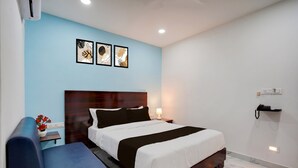 A modern hotel room with a large bed, bedside tables, a desk, and a blue sofa. - Townhouse Jeevan Bima Nagar Indranagar (Bangalore)