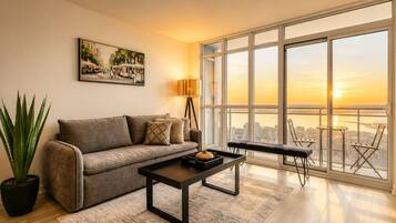 A modern living room with a sofa, coffee table, and a large window offering a city view.