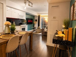 Una cocina moderna con un televisor de pantalla plana, un comedor con una mesa y sillas de madera, y una sala de estar con un sofá y una mesita de centro.