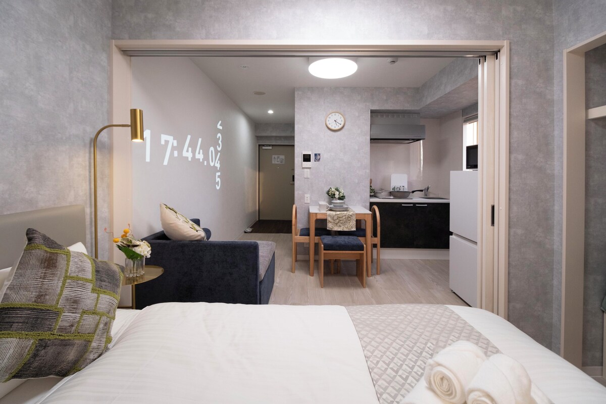 Ein modernes Hotelzimmer mit Bett, Schreibtisch und einer Küchenzeile.
