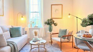Una sala de estar acogedora con un sofá, un sillón, una mesa de centro y una mesita de vidrio con un pastel.