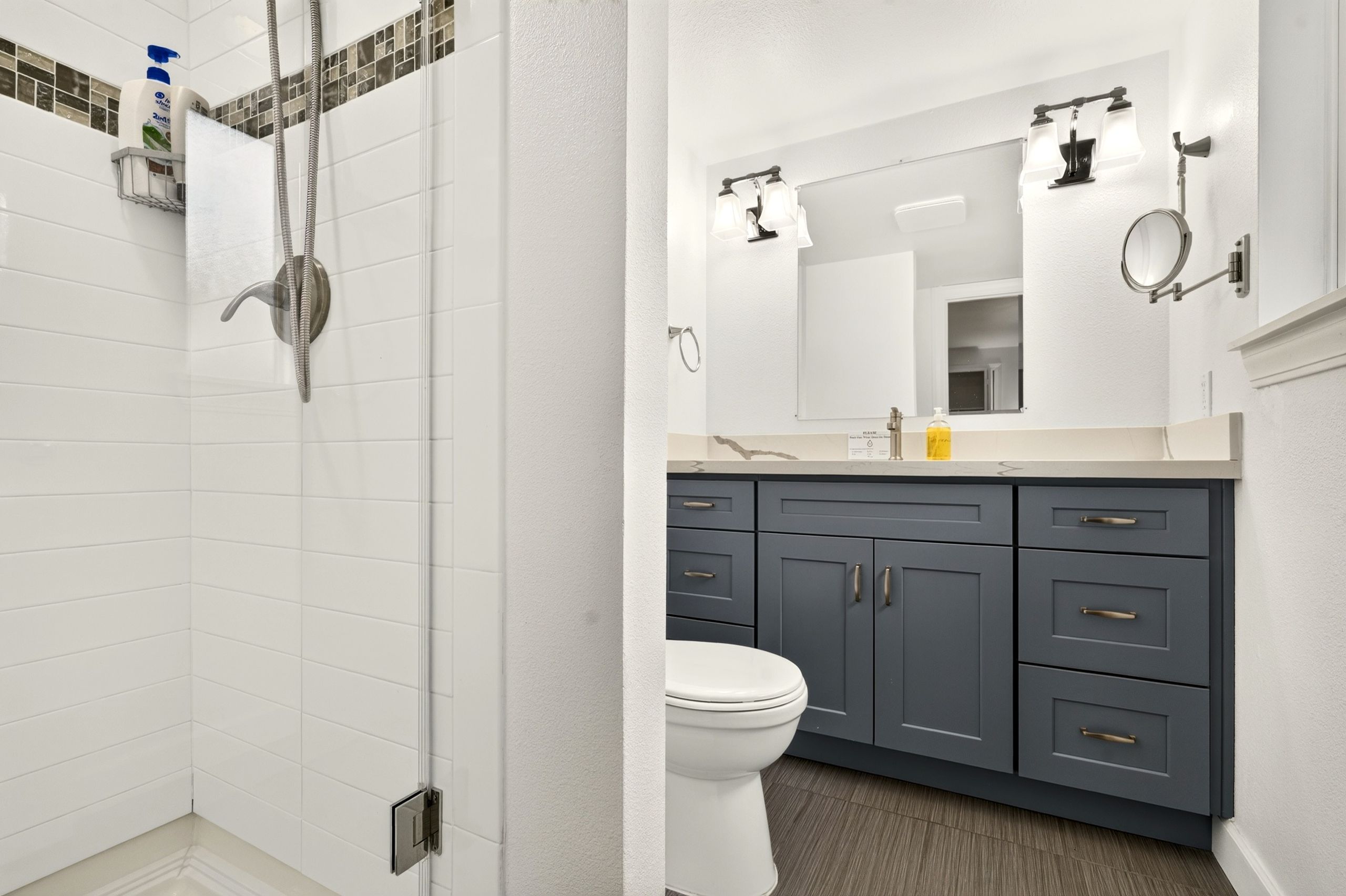 A bathroom with a shower, toilet, and vanity with cabinets.