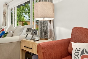 A modern living room with a sofa, a lamp, a television, and a wooden side table.