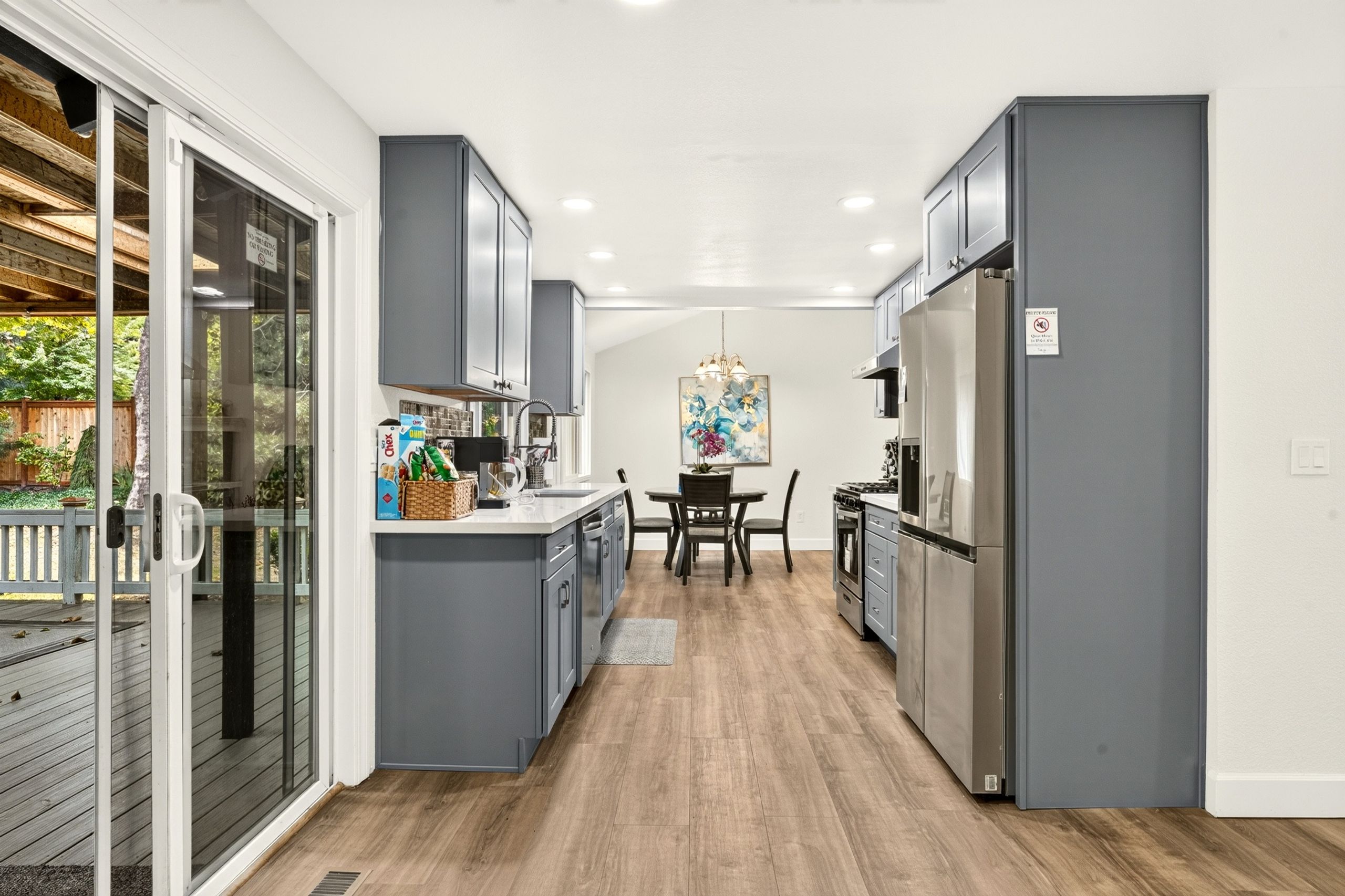 A modern kitchen with grey cabinets, a dining table, and a refrigerator.