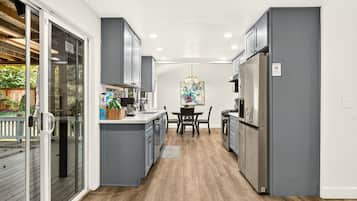A modern kitchen with grey cabinets, a dining table, and a refrigerator.