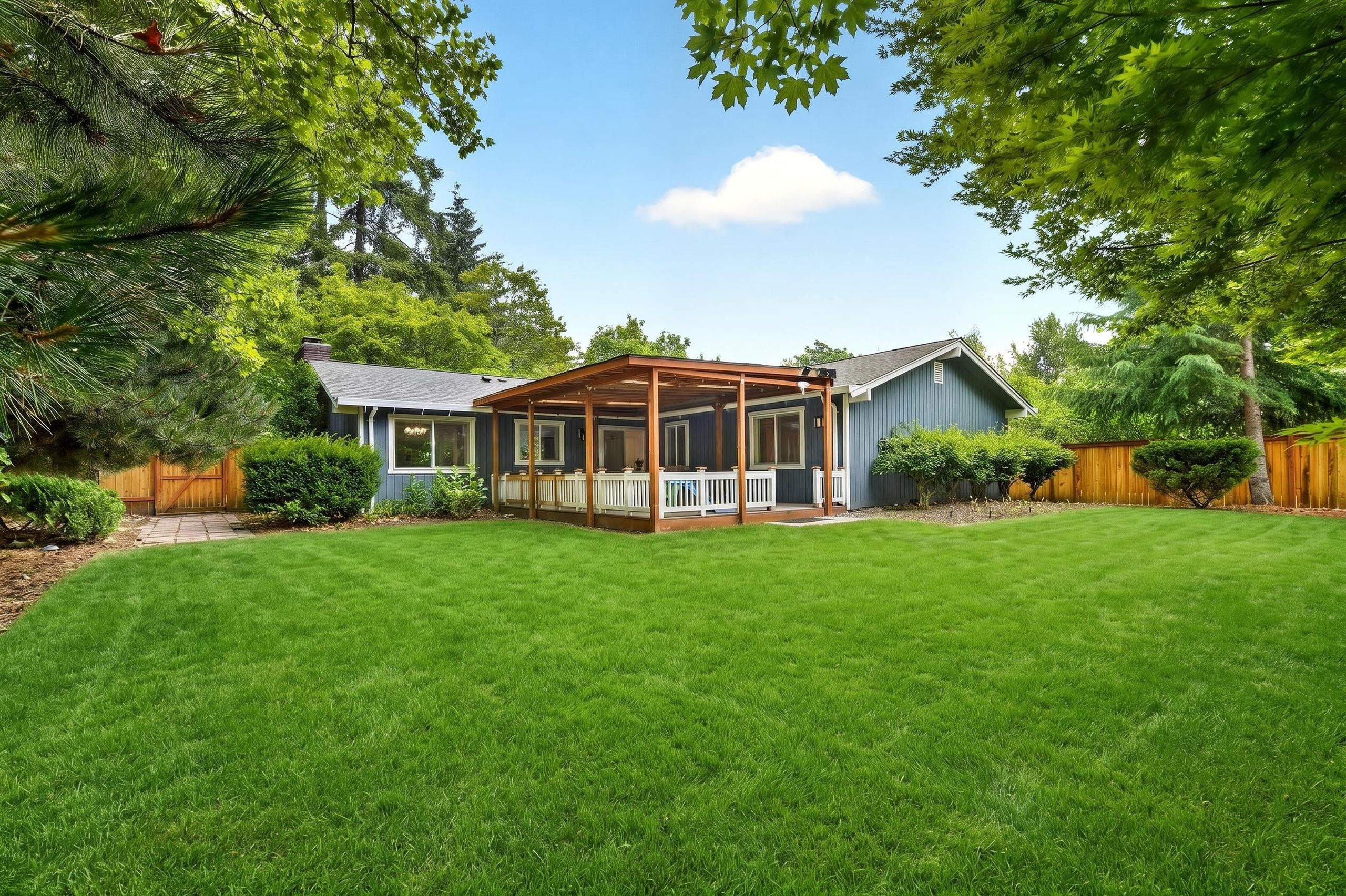 A house with a covered patio, a fenced yard, and a well-maintained lawn.