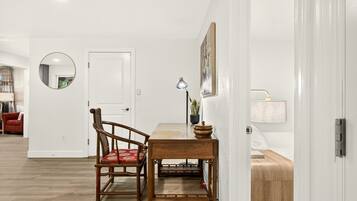 A dining area with a wooden table and chairs, a round mirror on the wall, and a door leading to another room.