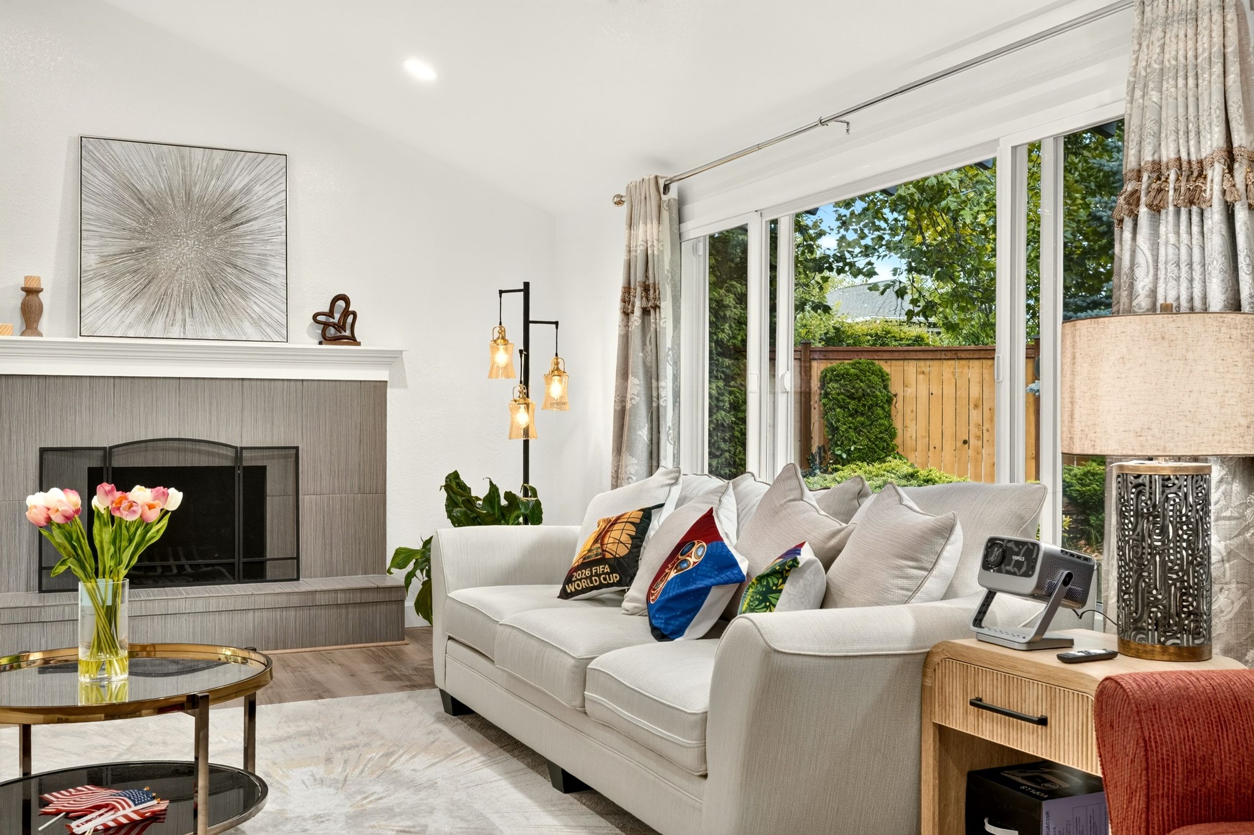 A modern living room with a fireplace, a sofa with decorative pillows, a coffee table, and a side table with a lamp.