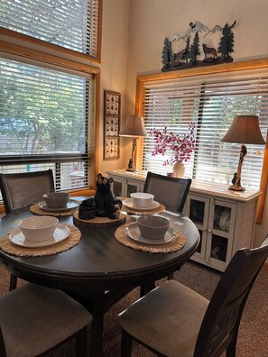 A dining area with a round table, four chairs, and two lamps. - Cabin in the pines with hot tub, wraparound porch, screened in patio, and yard. (Pinetop-Lakeside)