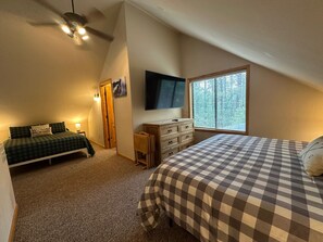 A bedroom with a bed, a dresser, a television, and a window. - Cabin in the pines with hot tub, wraparound porch, screened in patio, and yard. (Pinetop-Lakeside)