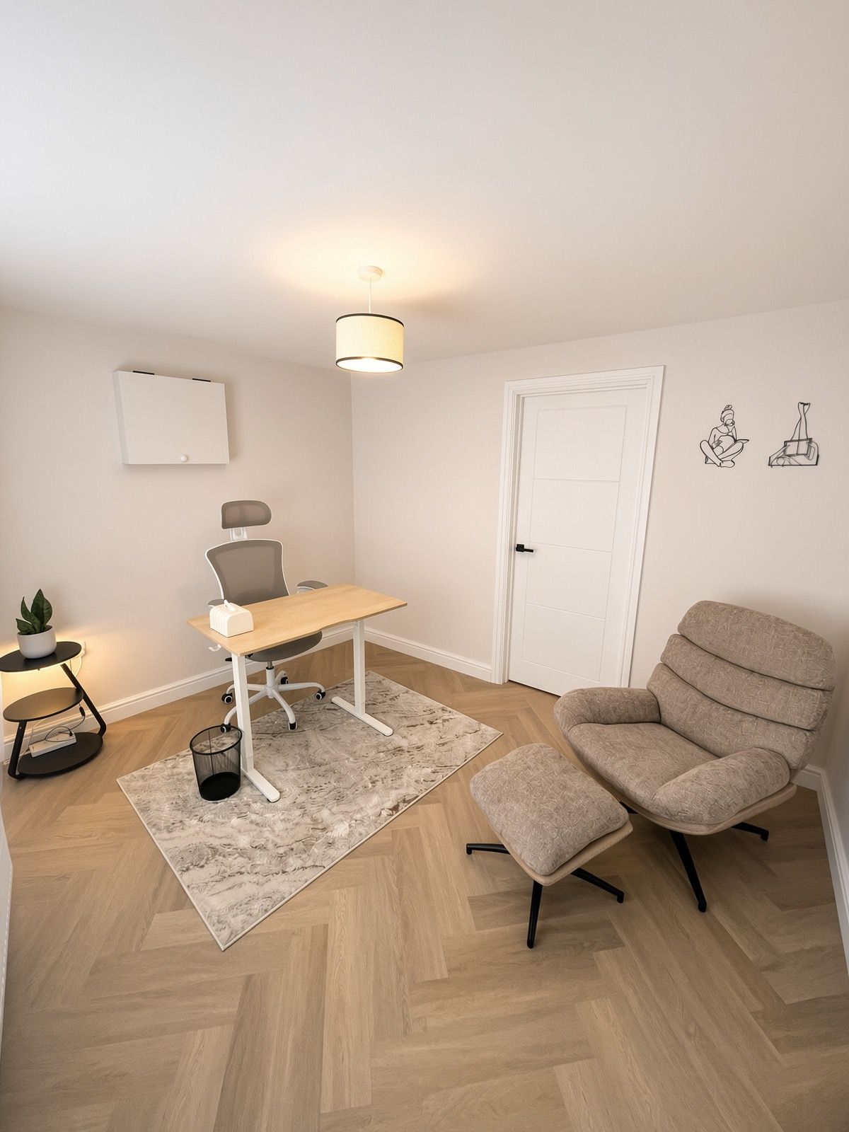 Ein Zimmer mit Schreibtisch, Stuhl und einem kleinen Tisch mit Pflanze.