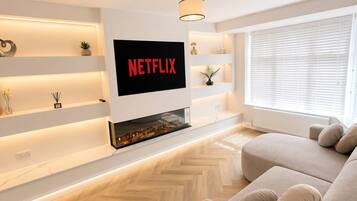 Ein modernes Wohnzimmer mit Flachbildfernseher an der Wand, einer Couch und einem Kamin.