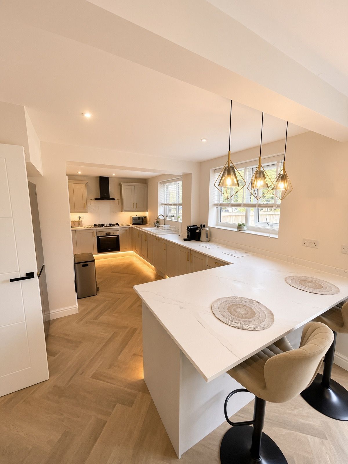 Eine moderne Küche mit einer zentralen Kochinsel, Pendelleuchten und Blick ins Freie.