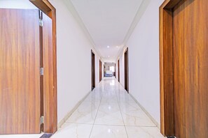 A corridor with wooden doors on both sides, leading to a reception area at the end. - Townhouse LIG Main Road Indore (Indore)