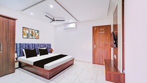 A bedroom with a bed, a ceiling fan, an air conditioning unit, a wardrobe, and a television. - Townhouse LIG Main Road Indore (Indore)