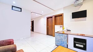A hotel reception area with a reception desk, a TV mounted on the wall, and a sign indicating the hotel is company-serviced. - Townhouse LIG Main Road Indore (Indore)