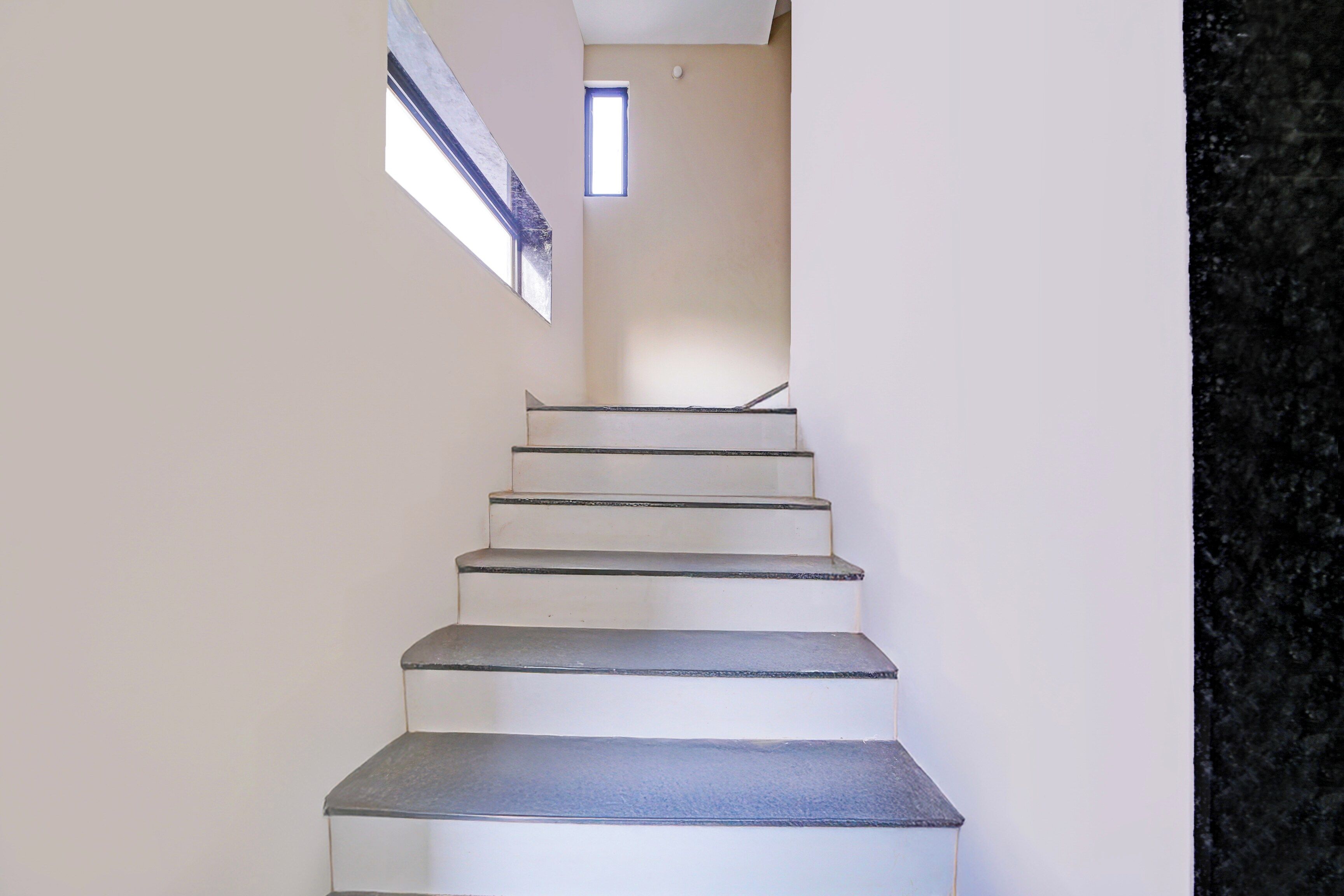 A staircase with a handrail and a small window at the top.