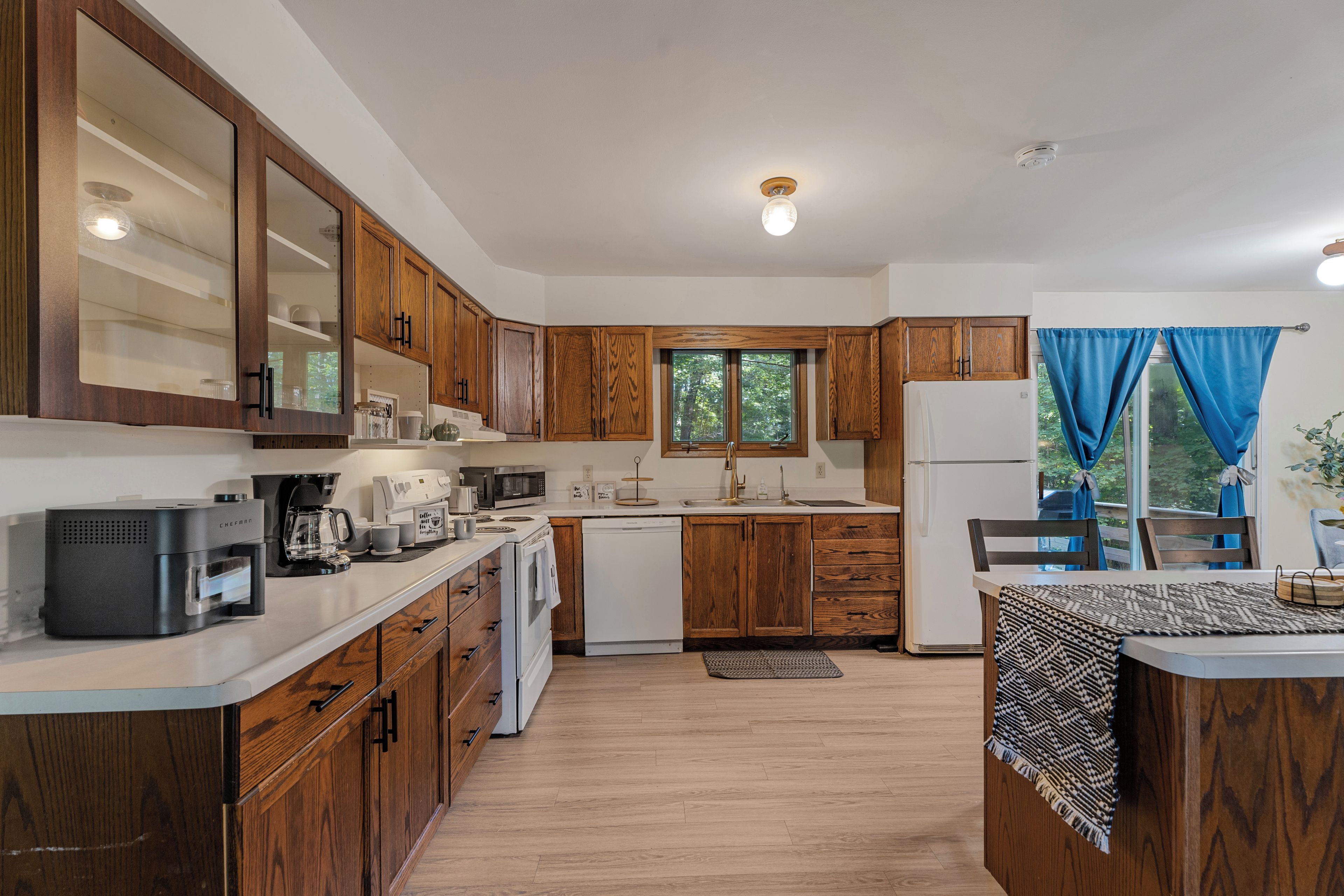 Una cocina moderna con armarios de madera, cafetera, microondas y refrigerador.