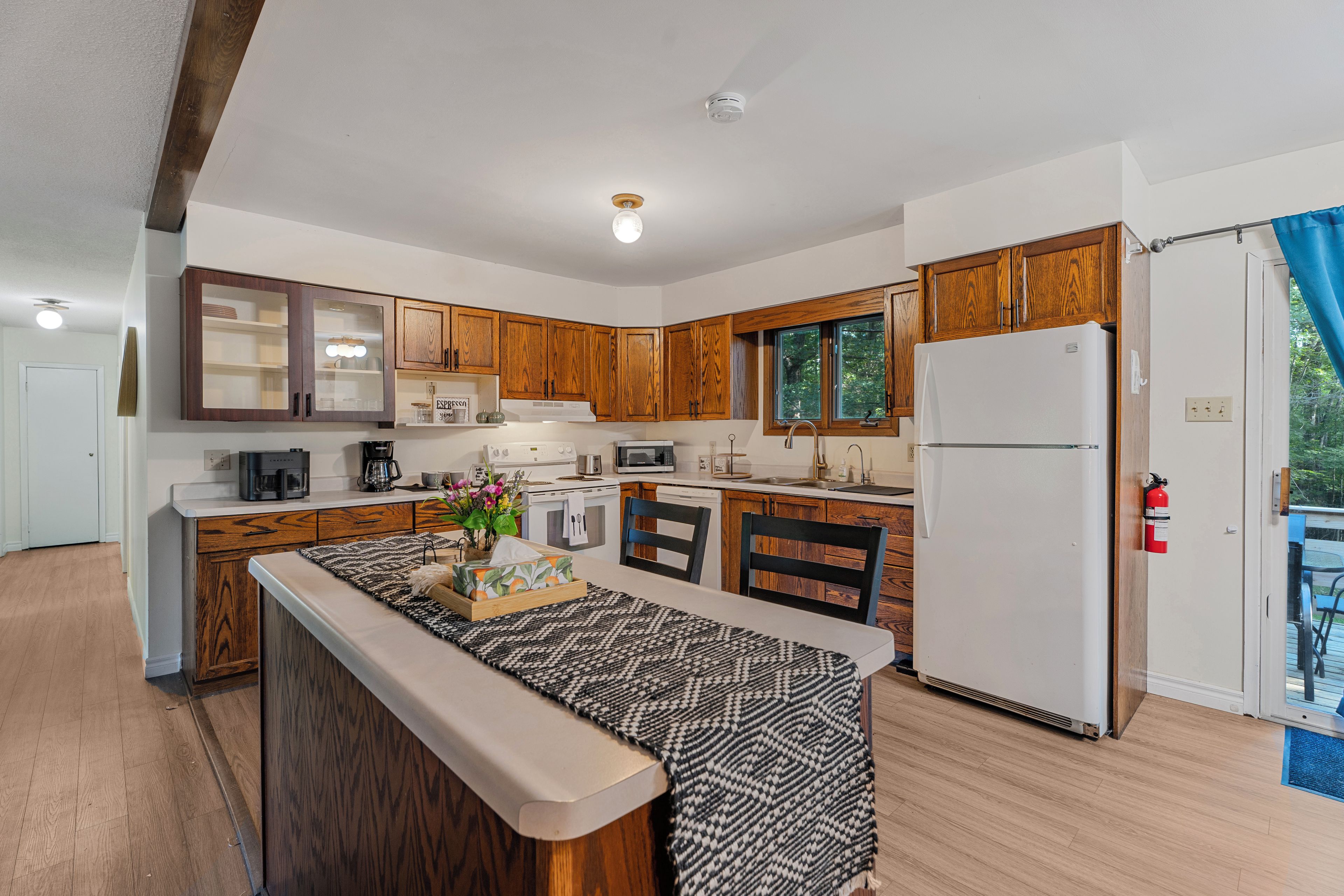 A modern kitchen with wooden cabinets, a central island, and a refrigerator.