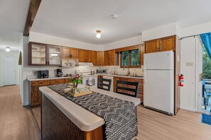 A modern kitchen with wooden cabinets, a central island, and a refrigerator. - Huntsville Retreat with Fire Pit, BBQ • Near Downtown (Huntsville)