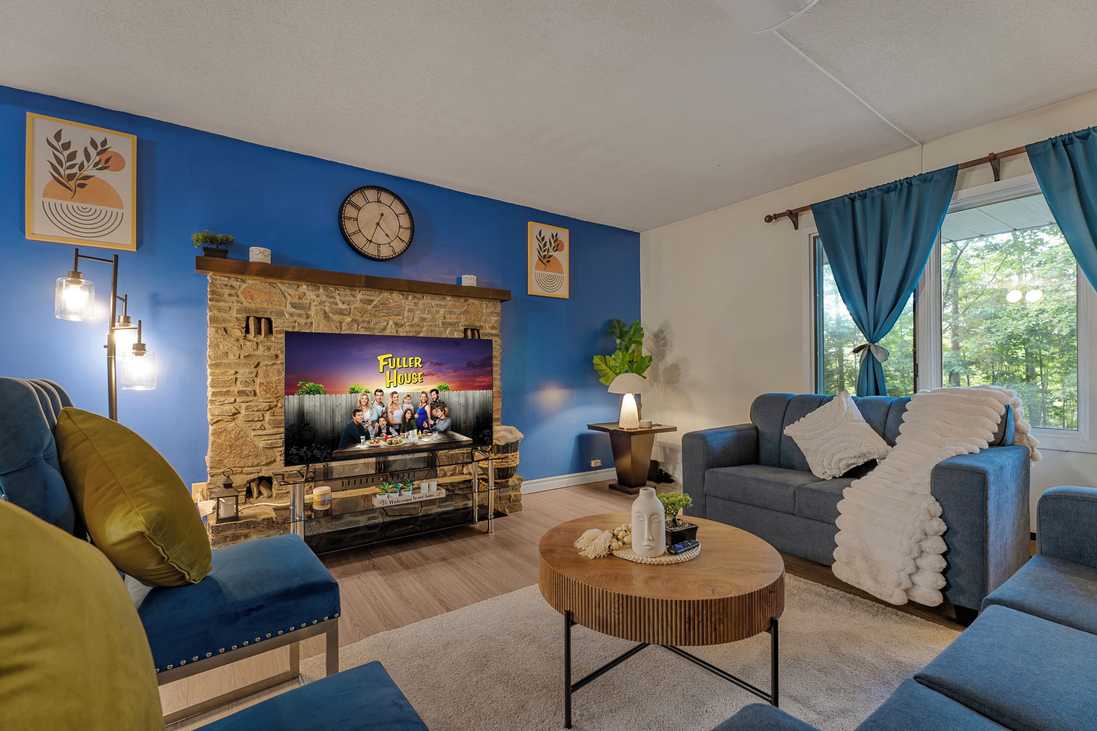 Una sala de estar con chimenea de piedra, paredes azules, un televisor y un sofá.