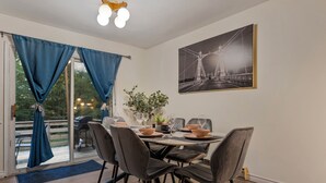 Zona de dinar amb una taula preparada per a quatre, una finestra gran amb cortines, i un quadre al mur.