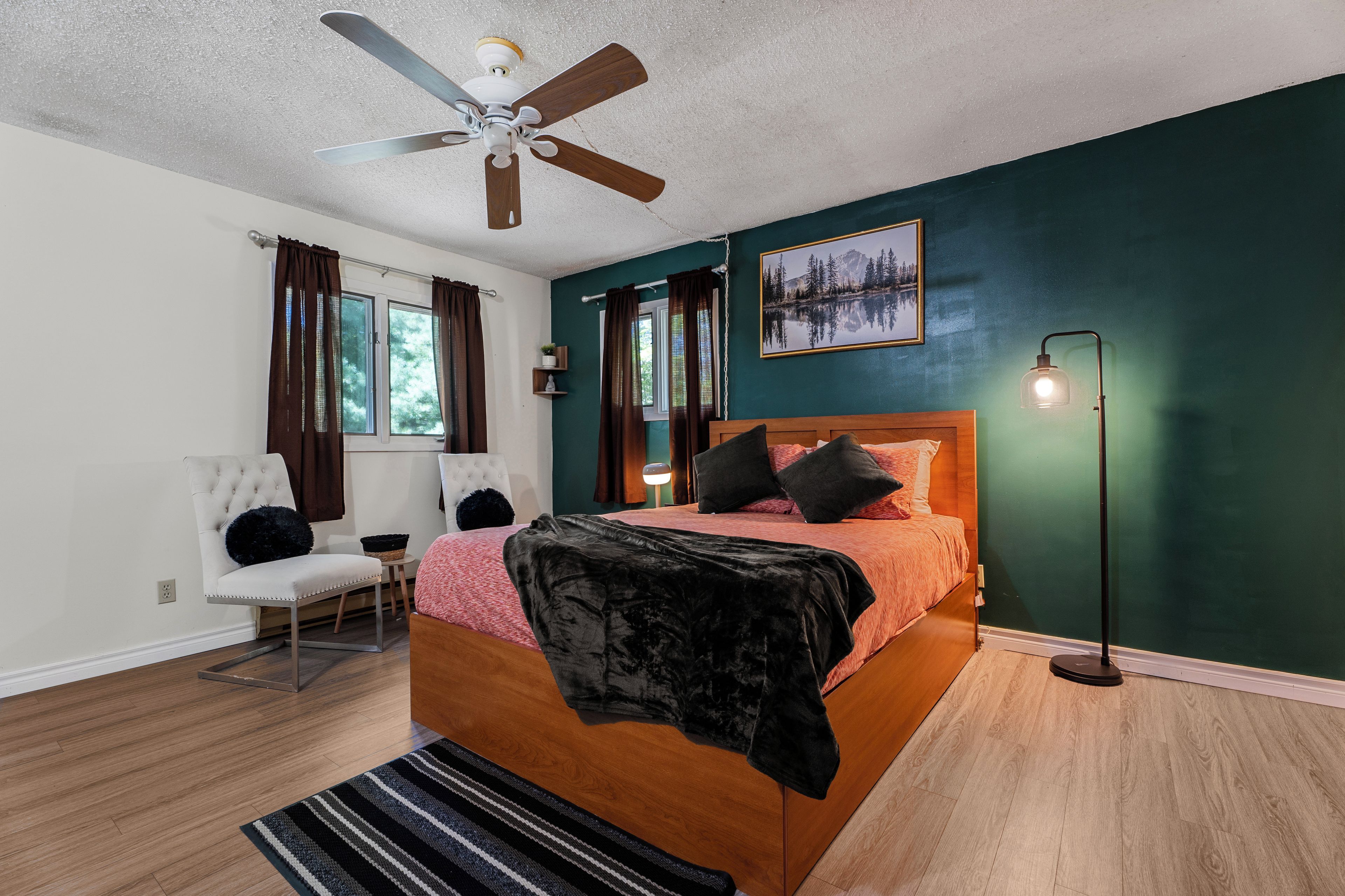 Ein Schlafzimmer mit einem Bett, einem Sessel, einer Stehlampe und einem Deckenventilator.