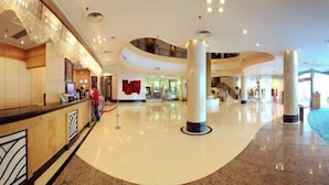 Un hall amplio con techo curvo, un mostrador de recepción y una columna central.