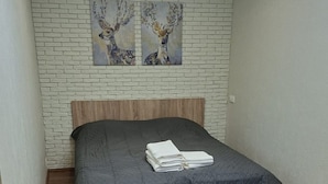 Un dormitorio con una cama, cabecera de madera y una pared con diseño de ladrillo.
