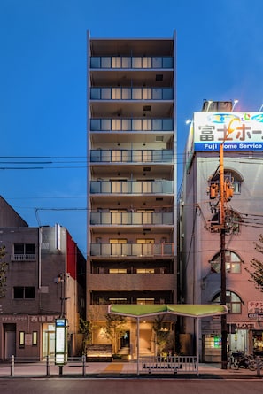 A multi-story building with a modern design, featuring balconies on each floor, a visible entrance with a green awning, and signage for a service company. - The Peak Osaka Bay (Misaki , Minato-ku, Osaka City)