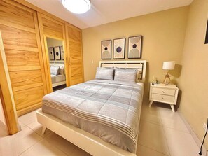 Un dormitorio con cama, mesita de noche, lámpara, armario y tres cuadros en la pared.