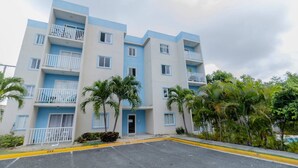 A multi-story residential building with balconies, a parking area, and surrounding greenery. - Serena Village | Pool, balcony, and near PUJ (Punta Cana)