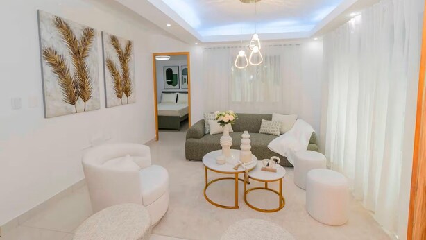 A modern living room with a sofa, two armchairs, a coffee table, and artwork on the walls. - Serena Village | Pool, balcony, and near PUJ (Punta Cana)