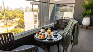 A balcony with a table set for breakfast, including croissants, fruit, and orange juice.