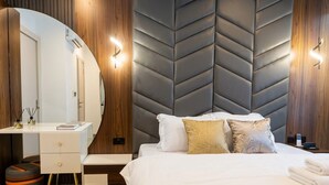 A hotel room with a bed, a desk, a mirror, and a modern wall design.